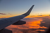 Passenger jet over clouds at sunset