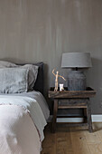 Bedroom in various shades of grey with wooden bedside table