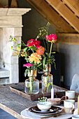 Blumenarrangement mit Dahlien und Pfingstrosen auf Holztisch im Landhausstil