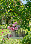 Bouquet of peonies (Paeonia) in vase hanging on tray in tree