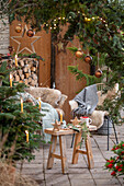 Weihnachtlich rustikal geschmückte Terrasse mit Sitzplatz vor Thuje und Christbaum mit Anhängern