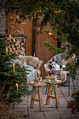 Weihnachtlich rustikal geschmückte Terrasse mit Sitzplatz vor Thuje und Christbaum mit Anhängern