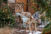 Weihnachtlich rustikal geschmückte Terrasse mit Sitzplatz vor Thuje und Christbaum mit Anhängern