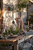 Weihnachtlich festlich gedeckter Tisch im Hüttenstil, Kiefernzapfen, Tannenzweige, Kerzenständer aus Glas