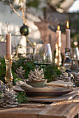 Weihnachtlich festlich gedeckter Tisch, Kiefernzapfen, Tannenzweige, Kerzenständer, Christbaumkugel