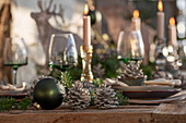 Weihnachtlich festlich gedeckter Tisch, Kiefernzapfen, Tannenzweige, Kerzenständer, Christbaumkugel