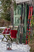 Sitzplatz im winterlichen Garten vor Hütte mit alten Skiern und Windlicht