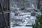 Hemlock wreath on barn door in front of snowy garden with seating area