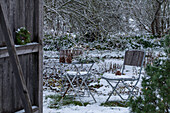 Hemlock wreath on barn door in front of snow-covered garden with seating area
