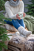 Frau mit weihnachtlicher Tasse und selbstgestrickten Socken 