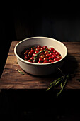 Bowl of cherry tomatoes and fresh herbs on a wooden table