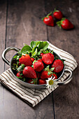 Fresh strawberries in a metal bowl on a wooden background