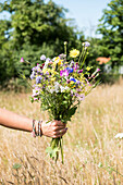 Bunte Wildblumen in der Hand im sommerlichen Garten