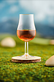 Glass of whisky on a mossy surface against a blurred mountain backdrop