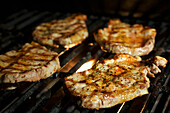 Four porks shoulder steaks on the barbeque