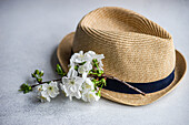 Straw hat with a sprig of white cherry blossoms