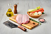 Raw chicken breast on a chopping board and vegetable ingredients