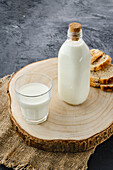 Bottle and glass with milk on a tree disc