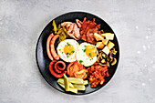 English breakfast with fried eggs, sausages and roasted vegetables