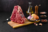 Raw porterhouse steak with spices and garlic on wooden board