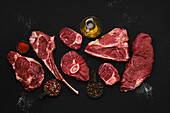 Various raw beef steaks with spices and olive oil