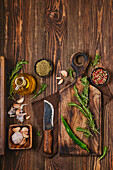 Still life with rosemary sprigs, garlic and spices on wooden board