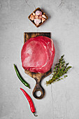 Raw beef topside in one piece with garlic, chilli and thyme