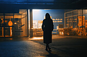 Silhouette of young woman in long coat