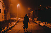 Silhouette of young woman walking through city at night