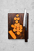 Sliced carrots on wooden board with knife