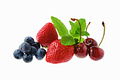 Erdbeeren, Kirschen, Heidelbeeren und Minze vor weißem Hintergrund