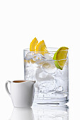 Glass with ice cubes and lemon slices; jug with espresso