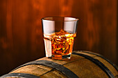 Whisky on the rocks in a tumbler on a wooden barrel