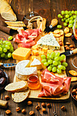 Cheese platter with ham, fruit, nuts and wine
