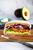 Vollkorn-Sandwich mit Hummus, Avocado und Gemüse