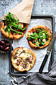 Mini-Pizzen mit Speck, Rucola, Oliven und roten Zwiebeln