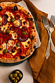 Pizza Diavolo mit Salami, Oliven, Paprika und roten Zwiebeln