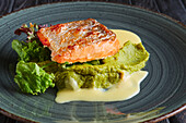 Fried salmon fillet on pea puree with salad and cream sauce