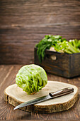 Iceberg lettuce with knife on wooden cutting board