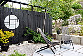 Modern garden area with black wooden chairs and Japanese-inspired fence