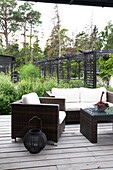 Garden seating area with rattan furniture and lantern on wooden deck