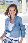 Young woman wearing a denim jacket, a white shirt and blue and white patterned trousers