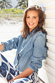 Young woman wearing a denim jacket, a white shirt and blue and white patterned trousers