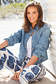 Young woman wearing a denim jacket, a white shirt and blue and white patterned trousers