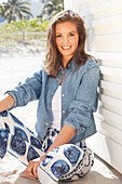 Young woman wearing a denim jacket, a white shirt and blue and white patterned trousers