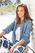 Young woman wearing a denim jacket, a white shirt and blue and white patterned trousers