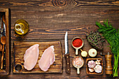 Raw chicken breast fillet with spices and herbs on a wooden table