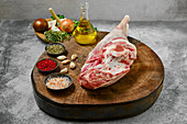 Raw leg of lamb with various spices on wooden board