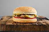 Hamburger in a sesame seed bun with gherkin and ketchup