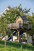 Wooden tree house with slide and swing in the garden